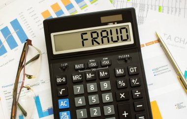 FRAUD etiketli bir hesap makinesi ofisteki mali belgelerde yatıyor. İş konsepti.