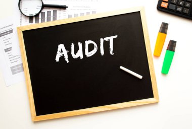 Tahtaya tebeşirle yazılmış AUDIT metni. Ofis masası ve ofis malzemeleri. İş konsepti.