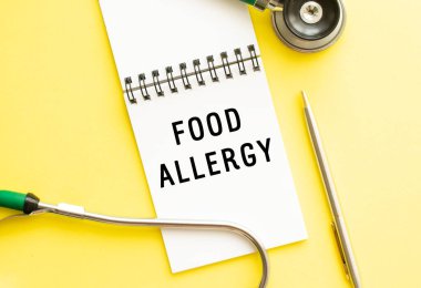 FOOD ALLERJY, kalem ve steteskopun yanındaki renk masasının üzerine yazılmış bir defter. Tıbbi konsept