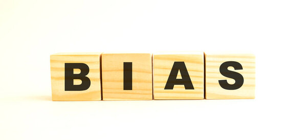 Слово БИАС. Деревянные кубики с буквами изолированы на белом фоне. Концептуальное изображение.