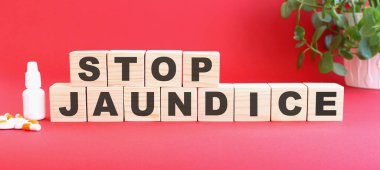 STOP JAUNDICE kelimesi tıbbi ilaçlarla kırmızı zemin üzerindeki tahta küplerden yapılmıştır..
