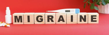MIGRAINE kelimesi kırmızı zemin üzerindeki tahta küplerden ve tıbbi ilaçlardan oluşur..