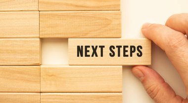 Elinizde, içinde NEXT STEPS yazan ahşap bir küp var. Pozitif düşünce konsepti