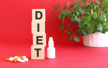 Diyet kelimesi kırmızı arka planda tıbbi ilaçlı tahta küplerden yapılmıştır..