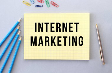 Kalem, ataç ve kağıt ataçlarının yanındaki gri arkaplan üzerine deftere yazılmış internetteki işaretleme metni. Kavram.