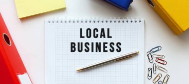 Beyaz bir arkaplanda, belge klasörünün ve ofis malzemelerinin yanında LOCAL BUSINESS mesajı olan bir not. İş konsepti.