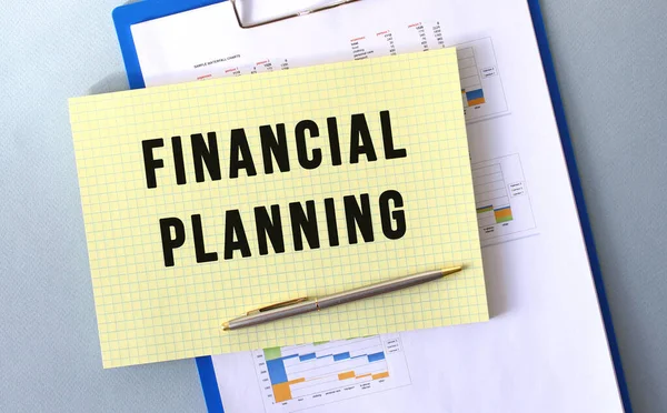 FINANCIAL PLANNING text written on notepad with pencil. Notepad on a folder with diagrams. Financial concept.