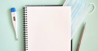 Not defterinde tıbbi koruyucu maske ve termometre var. Tıbbi konsept.