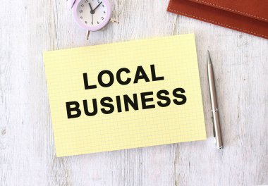 Ahşap bir çalışma masasında duran bir deftere yazılmış LOCAL İŞ metni. İş konsepti.