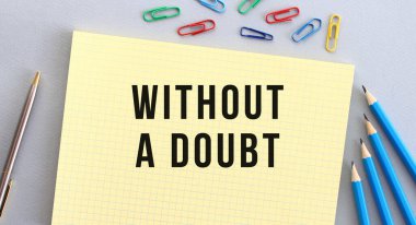 Not defterinde kalemlerin, ataçların ve ataçların yanındaki gri arkaplandaki bir DOUBT metni olmadan. Kavram.