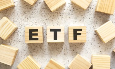 ETF kelimesi, üzerinde harfler olan tahta küplerden oluşur, arka planda üst görünüm. Çalışma alanı.