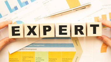 Çalışma masasının üzerinde uzman harfleri olan tahta küpleri tutan elleri kırpılmış görüntü. Üst görünüm