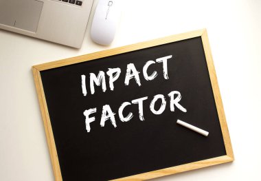 Tahtaya tebeşirle yazılmış bir IMPACT FACTOR metni. Ofis masası İş konsepti.