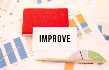 Üzerinde IMPROVE yazan beyaz kartvizit kırmızı kart sahibinin yanında duruyor. Mali konsept.