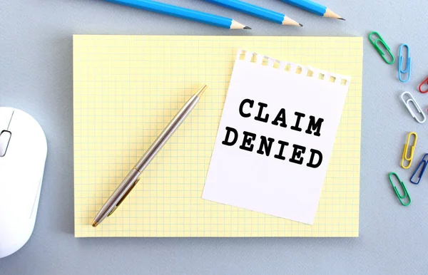 CLAIM DENIED, ofis malzemelerinin yanındaki deftere yazılmış bir kağıt parçasına yazılmıştır. İş konsepti.