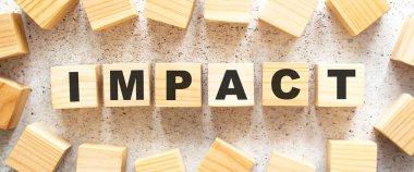 IMPACT kelimesi, üzerinde harfler olan tahta küplerden oluşur. Işık arkaplanının üst görüntüsü. Çalışma alanı.