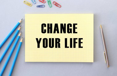 Kalem, ataç ve kağıt yanında gri arkaplan üzerine yaşam metninizi değiştirin. Kavram.