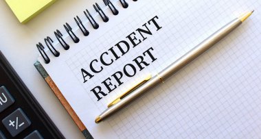 Metin ACCIDENT REPORT ile not, onun yanında bir hesap makinesi ve sarı not kağıtları yatar.