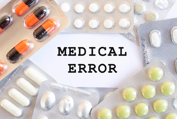Text MEDICAL ERROR on a white background. There are different medicines around. Medical concept.