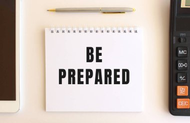 Hesap makinesi, tablet ve kalemin yanında, beyaz bir arkaplan üzerinde hazırlanan metin ile not.