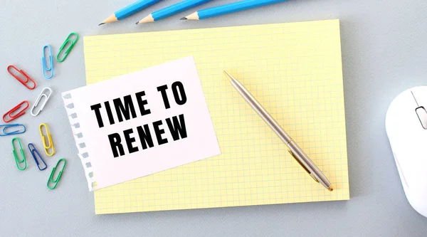 TIME TO RENEW is written on a piece of paper that lies on a notebook next to office supplies. Business concept.