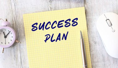 Tahta bir çalışma masasının üzerinde duran not defterine yazılmış berbat bir plan metni. İş konsepti.