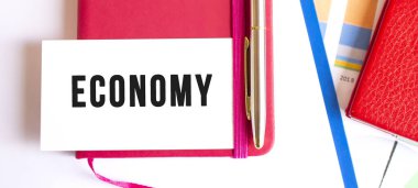 Not defterinin üzerinde duran beyaz kart üzerinde ECONOmy metni.