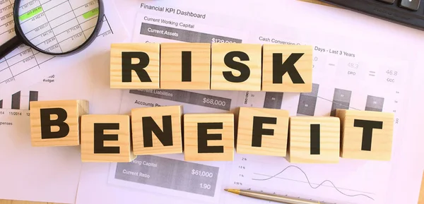 Wooden cubes with letters on the table in the office. Text RISK BENEFIT. Financial concept.