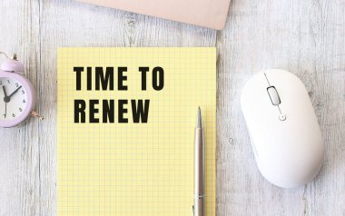 Dizüstü bilgisayarın yanındaki ahşap çalışma masasında duran bir deftere yazılmış metni yenileme zamanı. İş konsepti.