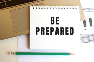 Laptop klavyesinde BE PrePARED metni olan not defteri var. En az çalışma alanı.