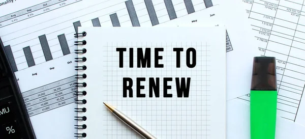 Text TIME TO RENEW on the page of a notepad lying on financial charts on the office desk. Near the calculator. Business concept.