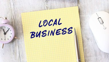 Ahşap bir çalışma masasında duran bir deftere yazılmış LOCAL İŞ metni. İş konsepti.