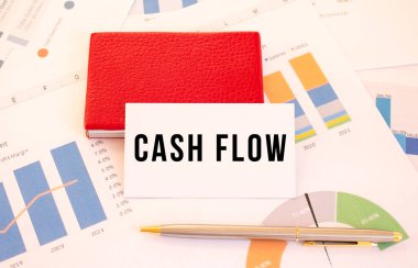White business card with text CASH FLOW lies next to red business card holder. Financial concept.
