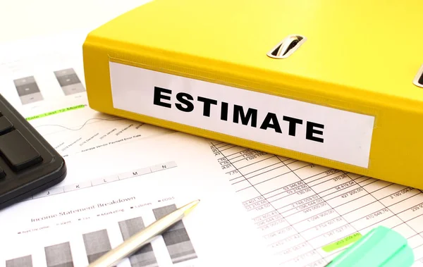 Üzerinde ESTIMATE yazan sarı bir klasör, ofis masasında mali tablolarla birlikte duruyor. Mali konsept.