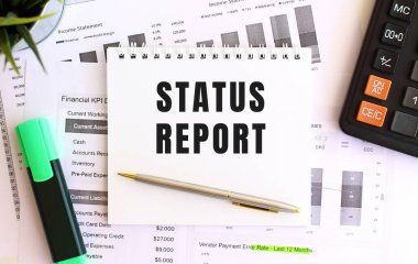 Beyaz arka planda, işaretleyicinin, hesap makinesinin ve ofis malzemelerinin yanında STATUS 'un yazılı olduğu not defteri. İş konsepti.