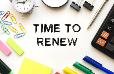 Hesap makinesi, büyüteç, renkli kalemler ve diğer kağıtlarla dolu beyaz ofis masası. Yenileme zamanı ile ilgili mesaj. Yukarıdan bak. İş konsepti.