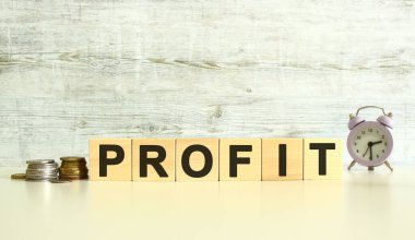 Üzerinde harfler olan altı tahta küp madeni paraların yanında masanın üzerinde. Kelime 