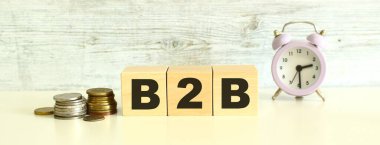 Bozuklukların yanındaki masada üç tahta küp ve harfler var. B2B kelimesi. Gri bir arka planda. Ön Görünüm Kavramları