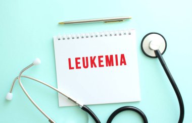 Kırmızı metinli beyaz not defteri LEUKEMIA ve mavi arka planda steteskop. Tıbbi konsept