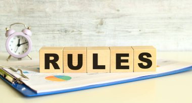 Tahta küpler, gri arka planda mali tabloların olduğu bir klasörde yatıyor. Küpler 