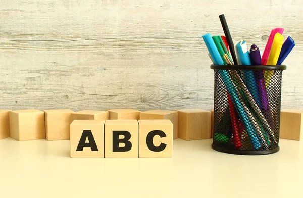 Three stacked wooden cubes with letters ABC on a white desktop on a gray background. Business concept