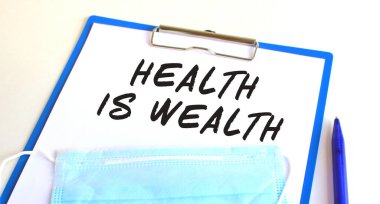 Masanın üzerinde tıbbi koruyucu maskeli bir pano var. Yazıtlara göre sağlık zengindir. Tıbbi konsept.