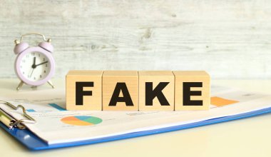 Tahta küpler, gri arka planda mali tabloların olduğu bir klasörde yatıyor. Küpler 