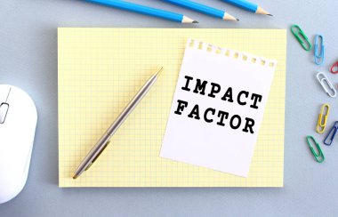 IMPACT FACTOR is written on a piece of paper that lies on a notebook next to office supplies. Business concept.
