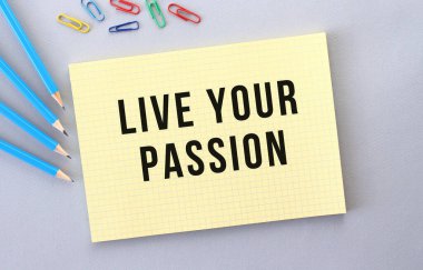 Gri arkaplandaki not defterinde kalem ve ataçların yanında yaşa. Kavram.