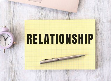 Not defterine yazılmış bir ilişki metni bir dizüstü bilgisayarın yanındaki ahşap çalışma masasında duruyor. İş konsepti.