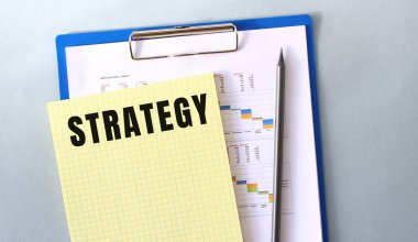 STRATEGY text written on notepad with pencil. Notepad on a folder with diagrams. Financial concept.