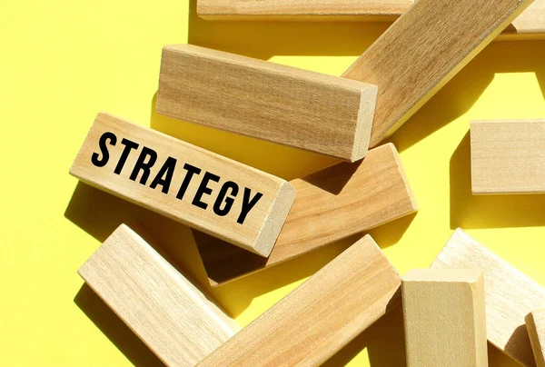 Strategy Text Written One Many Scattered Wooden Blocks Yellow Background — Stock Photo, Image
