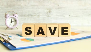 Tahta küpler, gri arka planda mali tabloların olduğu bir klasörde yatıyor. Küpler 