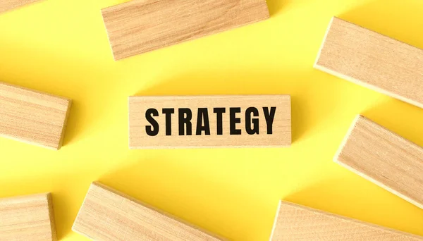 Das Wort Strategie Steht Auf Einem Holzklotz Auf Gelbem Hintergrund — Stockfoto